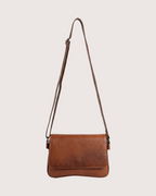 Tan leather crossbody bag on a light beige background