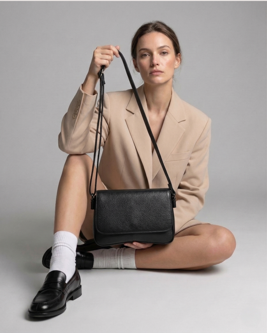 Woman holding a black handbag against a neutral background