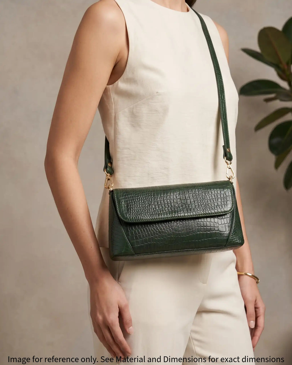 Woman carrying a green croc-embossed shoulder bag with gold hardware and modern elegant style
