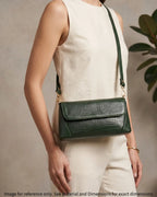 Woman carrying a green croc-embossed shoulder bag with gold hardware and modern elegant style