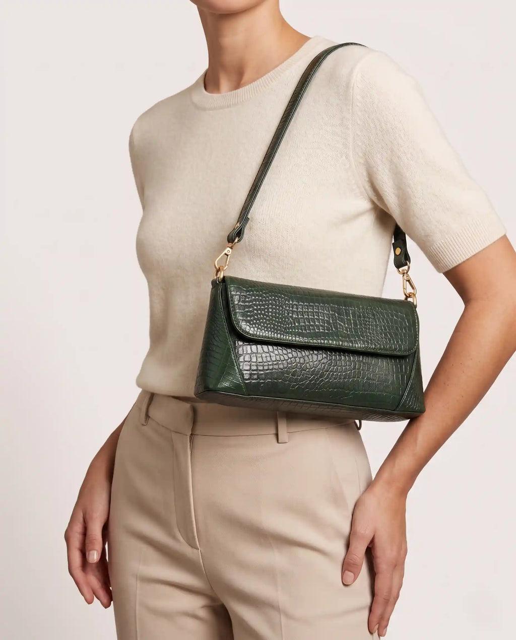 Woman carrying a green croc-embossed shoulder bag with gold hardware and modern elegant style