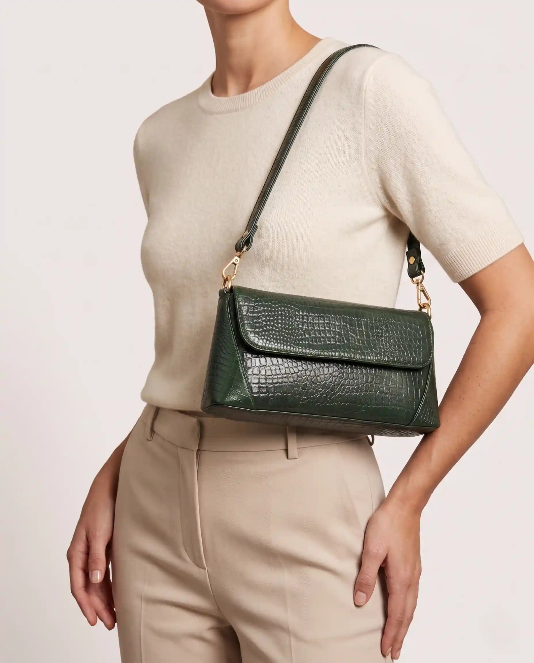 Woman carrying a green croc-embossed shoulder bag with gold hardware and modern elegant style