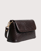 Side profile of brown crocodile-texture handbag with adjustable strap and sleek structured design