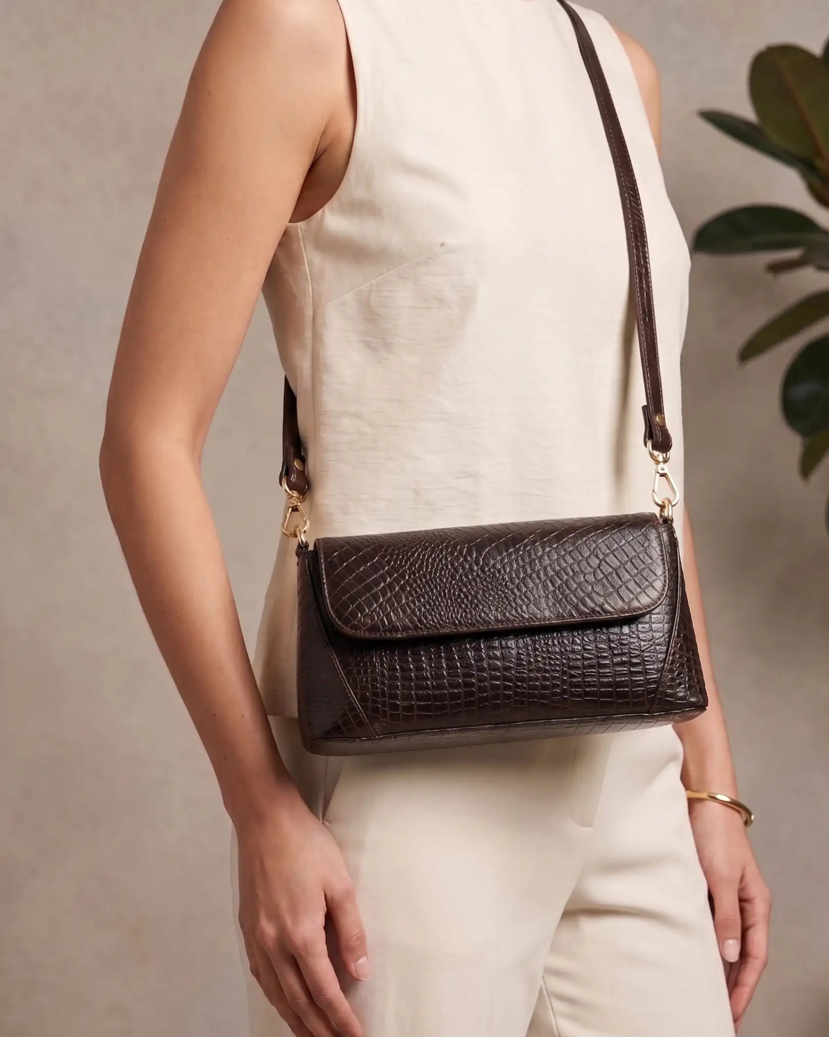 Woman carrying a brown croc-embossed shoulder bag with gold hardware and modern elegant style